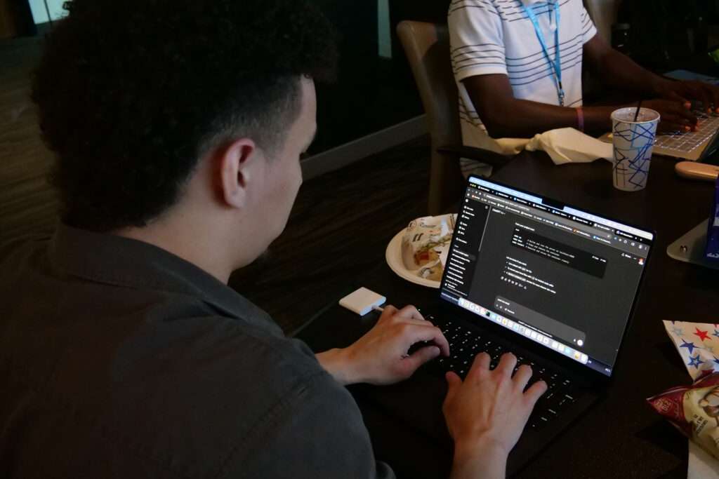 young student xtern sitting at laptop computer coding