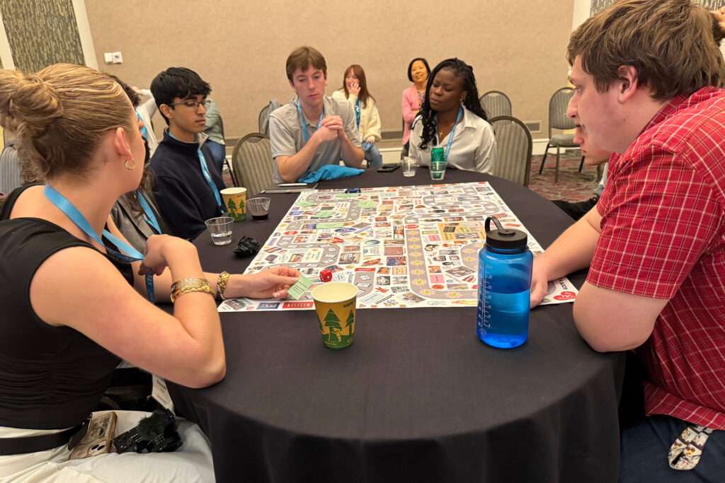 2025 xterns sitting at a round table participating in a board game challenge