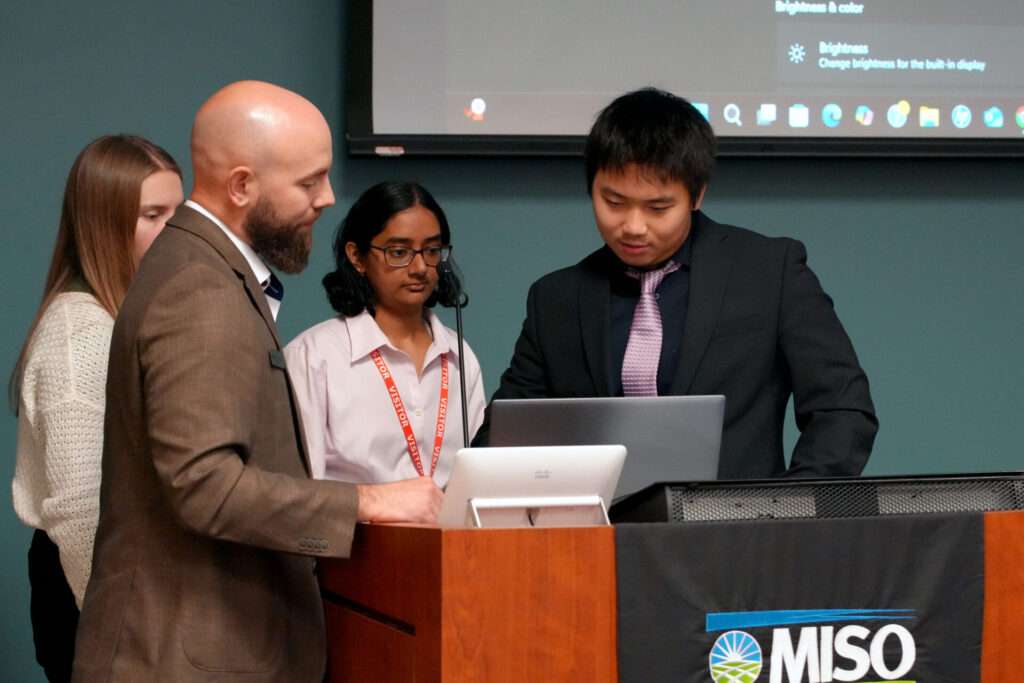 MISO's Todd Wickham helps Team 3's Kennedy Brown, Sriya Chakravarthula, and Weizhi Chen prepare to give their presentation in front of the MISO subject matter experts.