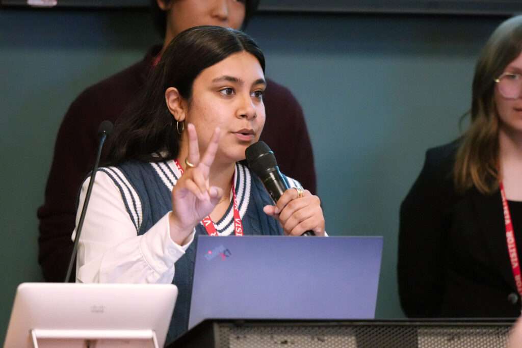 Maninder Kaur presents for Team 9 in front of a large audience, including MISO judges, at the Xtern Challenge.