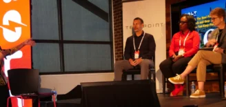 Moderator Linda Calvin leads a panel discussion at the BOLT Conference, powered by gener8tor and hosted by TechPoint. Three panelists sit on stage—Raman Ohri, Nicole Heatly-Holmes, and Carol Smith—discussing how organizations can adapt to rapid advances in tech and AI. A bright BOLT-branded display and WGU banner appear in the background.