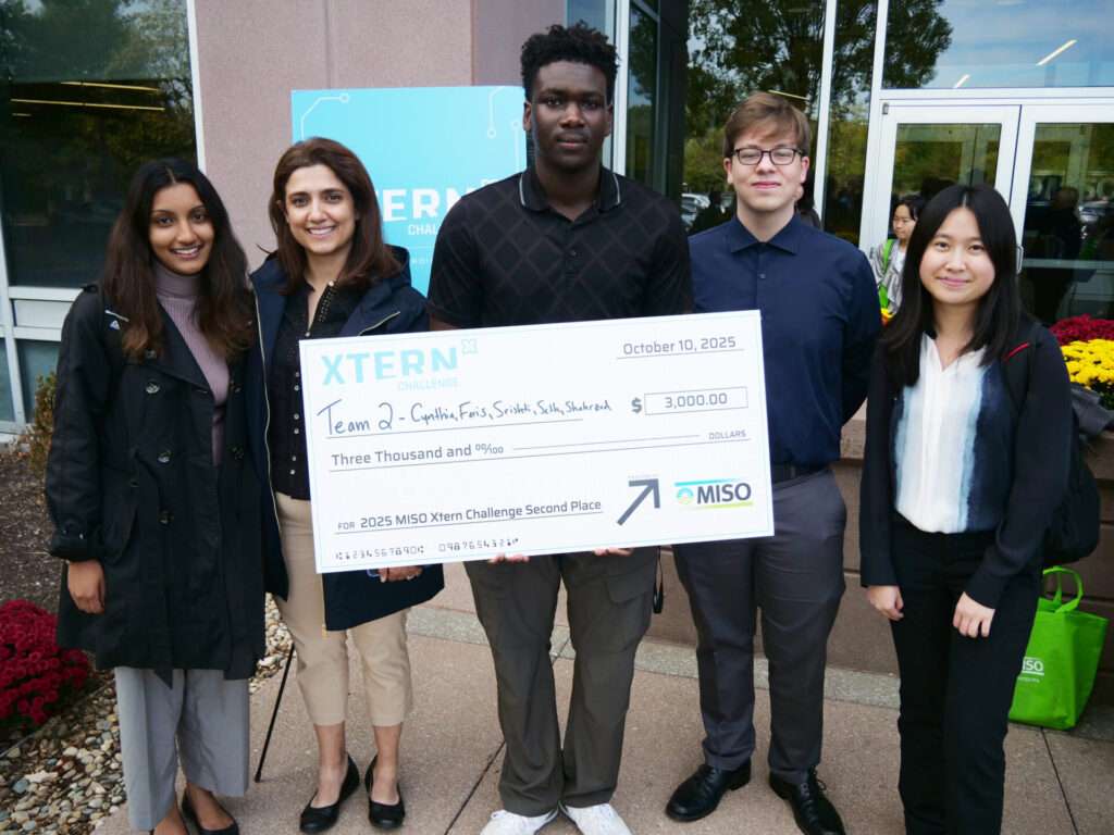 Team 2 members Srishti Maurya (Purdue University Indianapolis), Shahrzad Ghadiri (Purdue University), Faris Ibrahim (Purdue University Indianapolis), Seth Poindexter (Franklin College), and Cynthia Hu (University of British Columbia) pose outside MISO headquarters with their second-place check from the 2025 MISO Xtern Challenge.