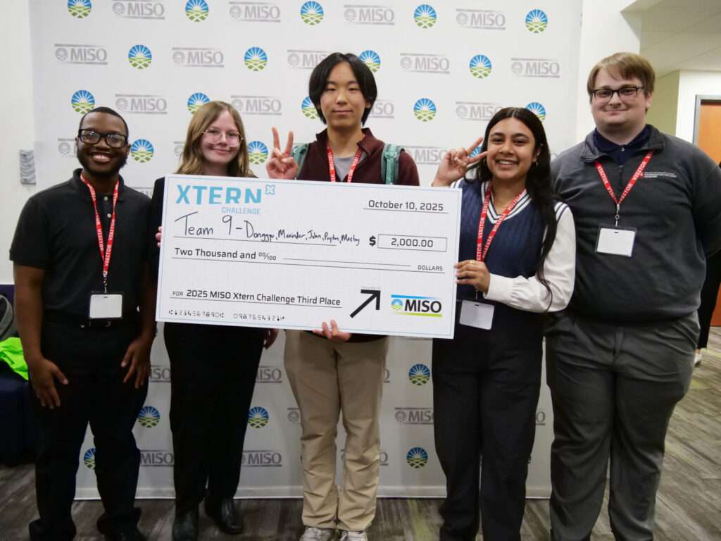 Team 9 members Peyton Silas (Indiana State University), Maeby Neaves (Indiana University Indianapolis), Donggyu Yoon (Purdue University), Maninder Kaur (Purdue University), and John Salata (Indiana University Indianapolis) pose in front of a MISO backdrop with their third-place check from the 2025 MISO Xtern Challenge.