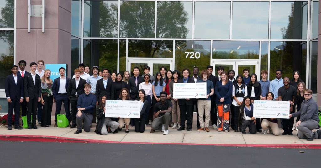 All 10 student teams from TechPoint’s 2025 Xtern Challenge pose together outside MISO headquarters in Carmel, Indiana. The photo includes the first-, second-, and third-place teams holding their award checks following the competition.