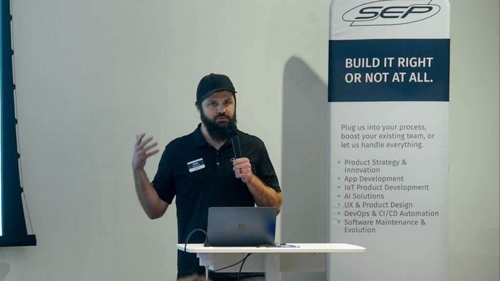 A SEP team member presents a case study at an event, speaking into a microphone beside a laptop, with a SEP banner behind him reading “Build it right or not at all.”
