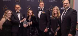 A group of six SEP team members stand together on the Mira Awards red carpet, dressed in formal attire and smiling as they hold the Exceptional Employer of the Year award.