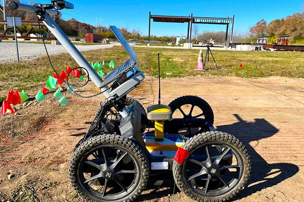 A ground rover performs an experiment in a field marked with red and green flags.