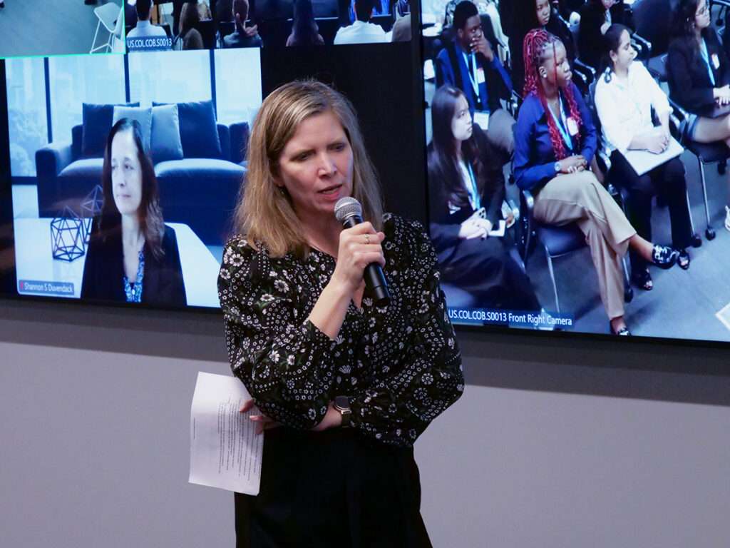 Jennifer Rumsey, Chair and CEO of Cummins, speaks to students during the 2026 Xtern Challenge. A video wall behind her shows remote participants and audience views from the event.