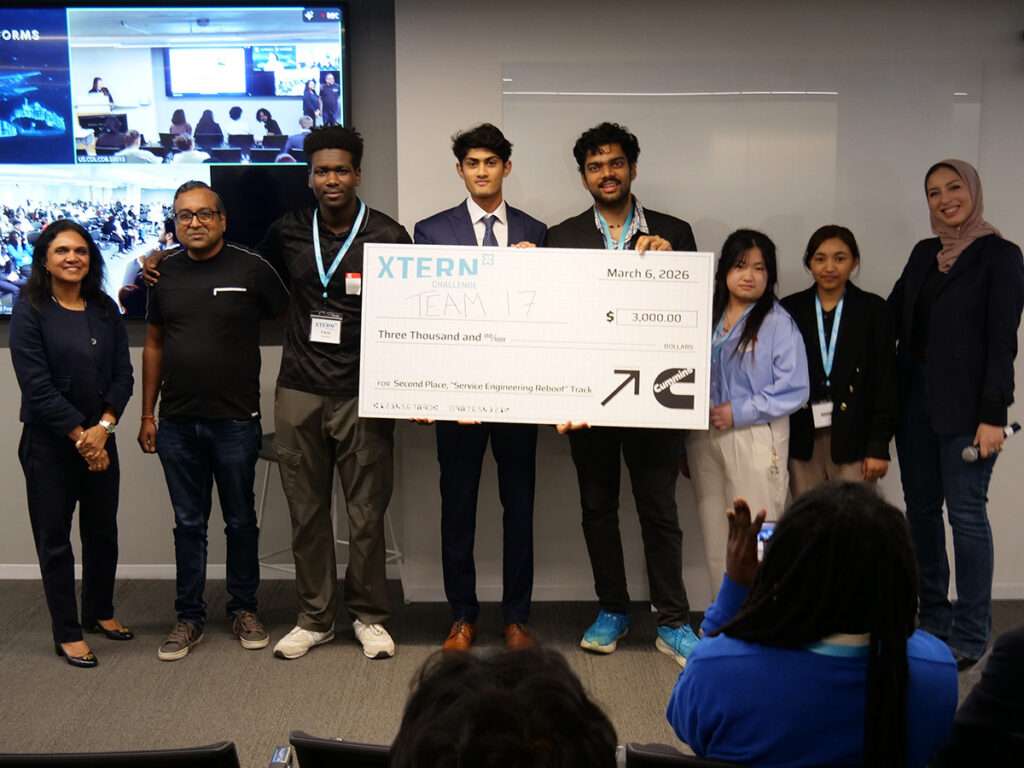 Team 17 poses with Cummins representatives and event staff while holding a ceremonial $3,000 check for second place in the Service Engineering Reboot track at the 2026 Xtern Challenge. Team members are Faris Ibrahim of Purdue University, Ahaan Kothari of Rose-Hulman Institute of Technology, Venkata Karthik Konduri and Key Weng of Indiana University Indianapolis, and Iota Shrestha of Purdue University.