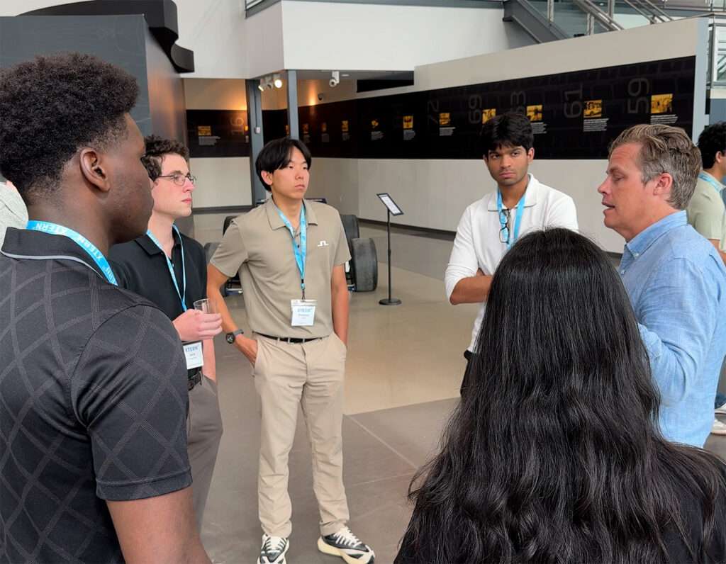 TechPoint CEO Eric Christopher speaks with a small group of Xterns wearing blue Xtern lanyards during an event at Dallara.