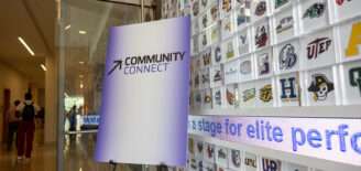 Community Connect signage stands inside the NCAA Hall of Champions beside a display featuring collegiate athletics logos.