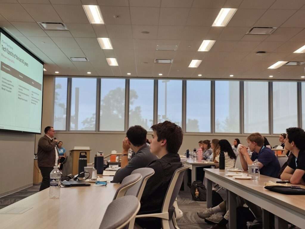 Chris Vannoy speaks at the Xtern AI Day keynote, with a slide on 'Tech Epochs of the Last 40 Years' displayed behind him.