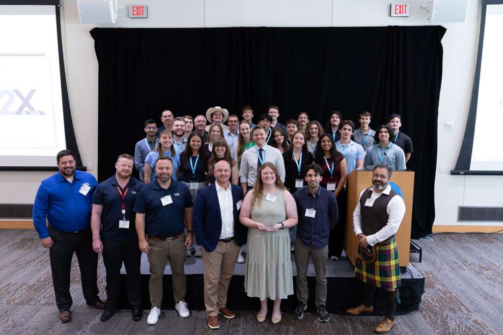 Members of the V2X team pose together onstage after receiving the 2026 XTERN Employer of the Year Award.