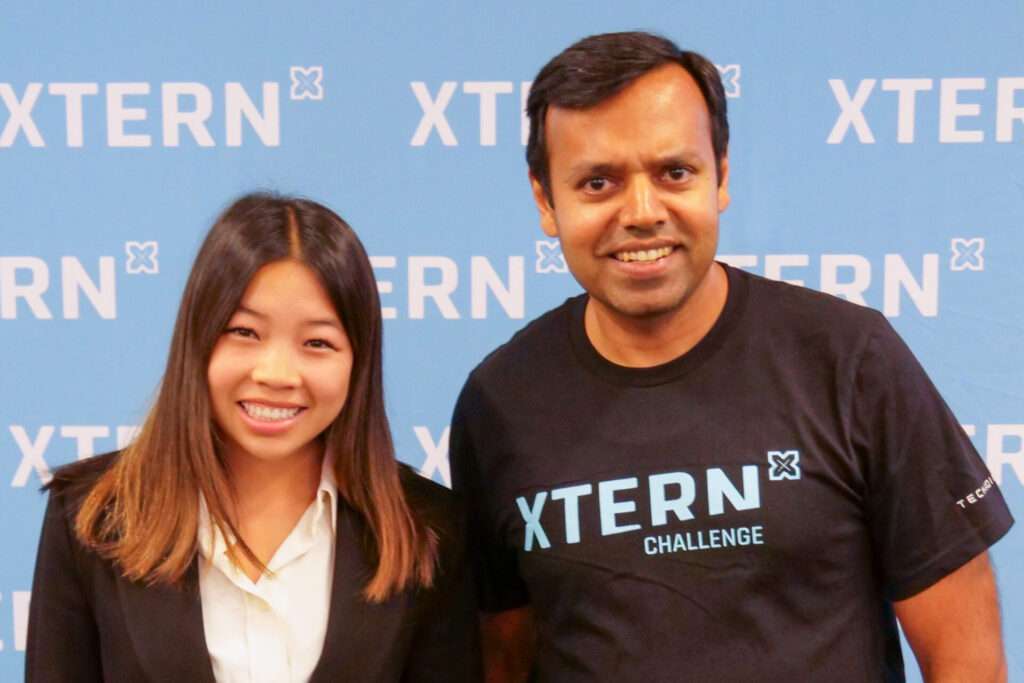 Ava Castonzo of Purdue University, winner of the Xtern Challenge Core Values Award, stands with Nirav Shah of MISO in front of an Xtern backdrop.